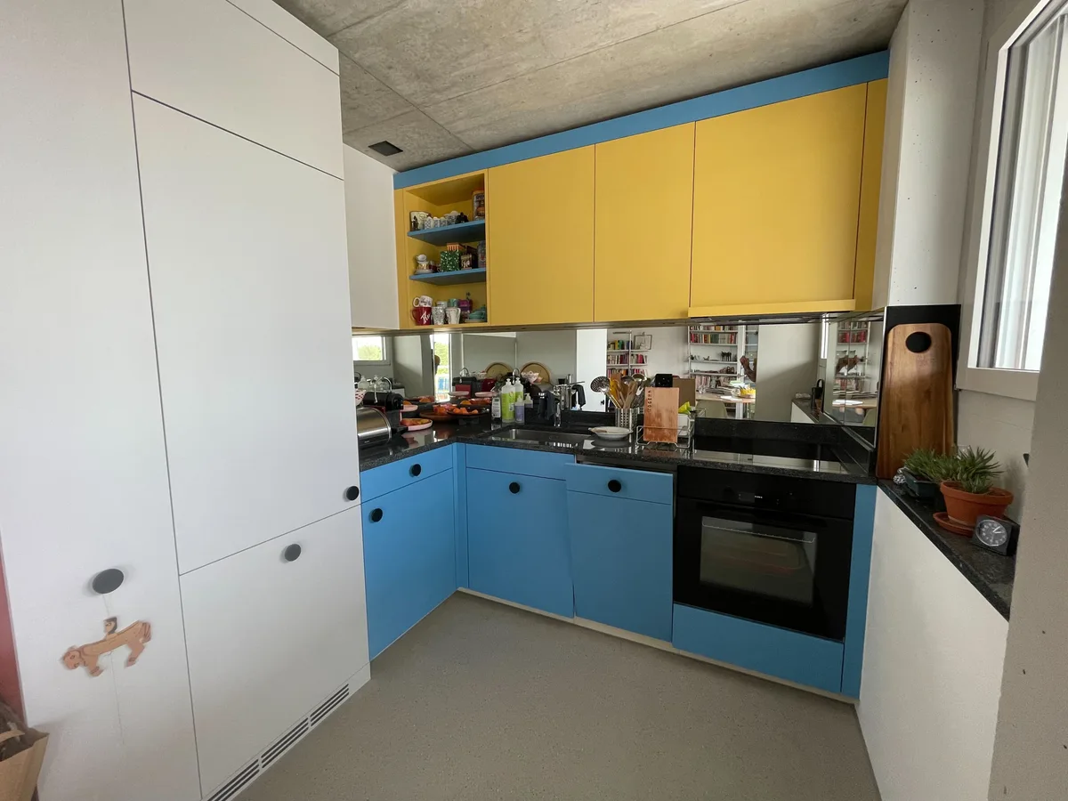 Die Küche verfügt über Backofen, Abwaschmaschine und Elektroherd.  Bild einer Küche mit bunter Front und Spiegeln.